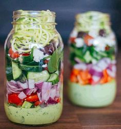 two mason jars filled with cucumber, red onion and other veggies