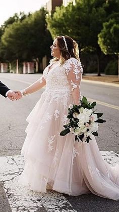 a bride and groom holding hands while walking down the street in their wedding gowns