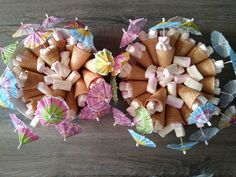 an arrangement of ice cream cones and umbrellas on a wooden table with other items