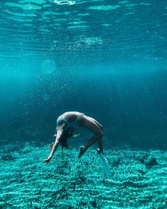 a woman is diving in the ocean with her legs spread out and head above water's surface