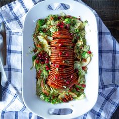 a white plate topped with meat covered in lettuce and pomegranate