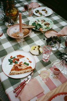 a table topped with plates and pizza on top of a checkerboard table cloth