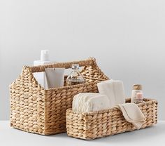 two wicker baskets with towels, soap and lotion in them on a white surface