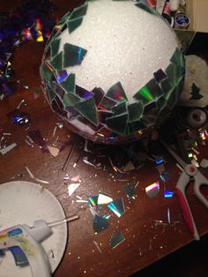 a disco ball sitting on top of a wooden table next to scissors and confetti