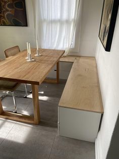 a wooden table sitting next to a window in a room with white walls and flooring