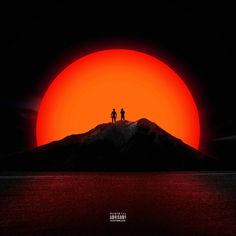 two people standing on top of a mountain with the sun in the sky behind them