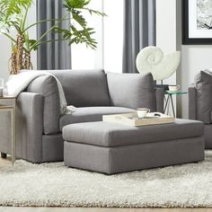 a living room scene with focus on the couch and chair, coffee table and ottoman