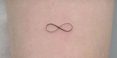 an infinite symbol tattoo on the back of a woman's left thigh, with black ink