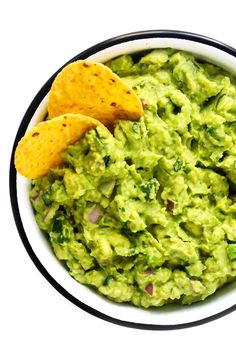 a bowl filled with guacamole and tortilla chips on the side