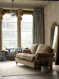 a living room filled with furniture next to a window covered in drapes and curtains