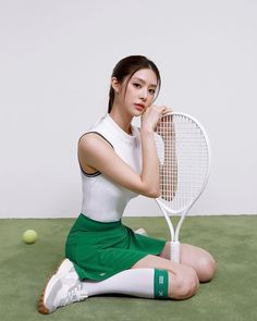 a woman sitting on the ground with a tennis racket