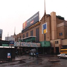 a city street with cars parked on the side of it and people walking in the rain