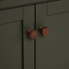 two wooden knobs on the side of a green cabinet