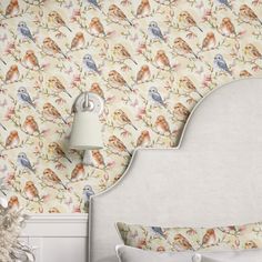 a white bed sitting in a bedroom next to a wallpaper with birds on it