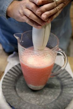 a person pouring something into a blender on top of a plate with a spoon