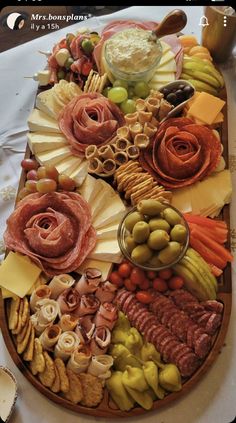 a platter filled with meats, cheeses and olives on a table