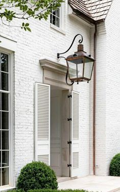 a white brick building with a lamp post and bushes