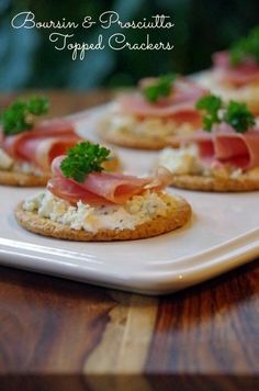 small crackers topped with prosciutto and parsley on a white plate