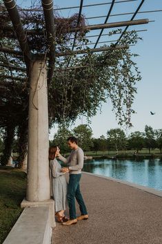 a man and woman standing next to each other under a pergoline covered structure