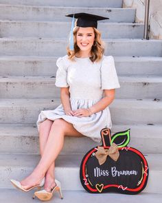 a woman sitting on the steps wearing a graduation cap and gown with her hand in her pocket