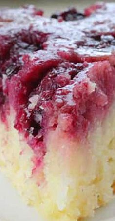 a close up of a piece of cake on a plate with blueberries and raspberry sauce