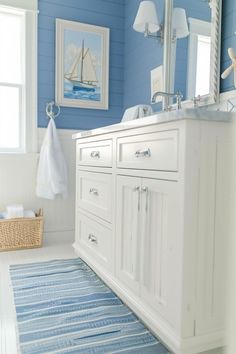 a bathroom with blue walls and white cabinets is pictured in this image, it has a rug on the floor