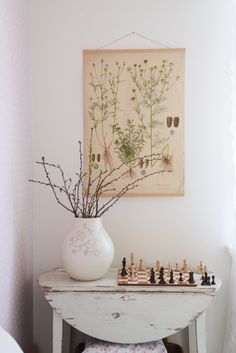 a vase with flowers and chess pieces on a small table in front of a window