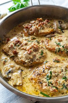 a pan filled with meat covered in gravy next to mushrooms and parsley