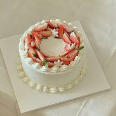 a white cake topped with fresh strawberries on top of a table