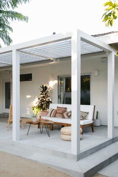 an outdoor living area with white furniture and plants