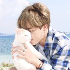 a person holding a white cat near the ocean