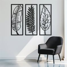 a chair sitting in front of three metal wall art pieces on a white wall next to a window