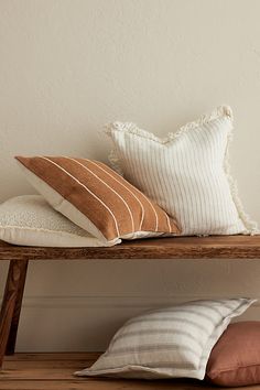 three pillows sitting on top of a wooden shelf