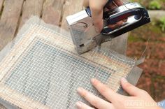 someone is using a pair of scissors to cut fabric on a piece of wood plank