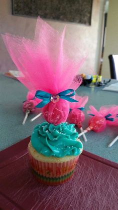 a cupcake with pink and blue frosting on it sitting on top of a table