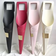 three different colored wine bottles with gold labels on them, one is black and one is pink