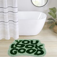 a bathroom rug that says you look good on the floor next to a bathtub