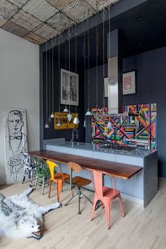 a kitchen with colorful chairs and artwork hanging from the ceiling