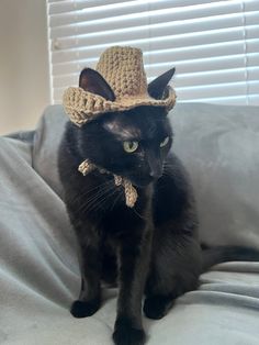 a black cat wearing a crocheted hat on top of a bed