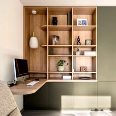 a desk with a monitor, keyboard and bookshelf in the middle of it