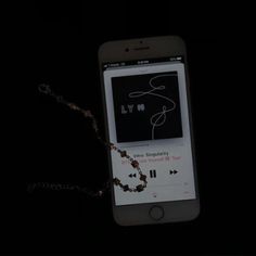 an iphone with a rosary attached to it's display screen in the dark,