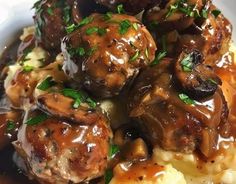 meatballs covered in gravy and mushrooms on top of mashed potatoes