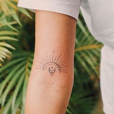 a woman's arm with a small sun and moon tattoo on the left forearm