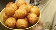 a person holding a yellow bowl filled with doughnuts