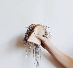 a person holding a piece of bread that has been toasted and sprinkled with silver foil