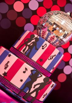 a disco ball sitting on top of two stacked gift wrapped in pink and purple ribbon