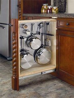 an open cabinet with pots and pans on it in the middle of a kitchen