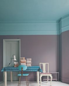 a room with two chairs and a table covered in books on top of the floor