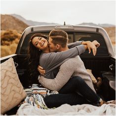 a man and woman hugging in the back of a pickup truck