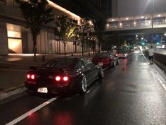 several cars are parked on the side of the road in the rain at night time